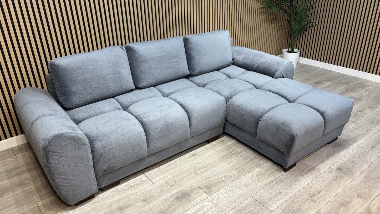 Gray sectional sofa in a room with wooden flooring and a striped wall.