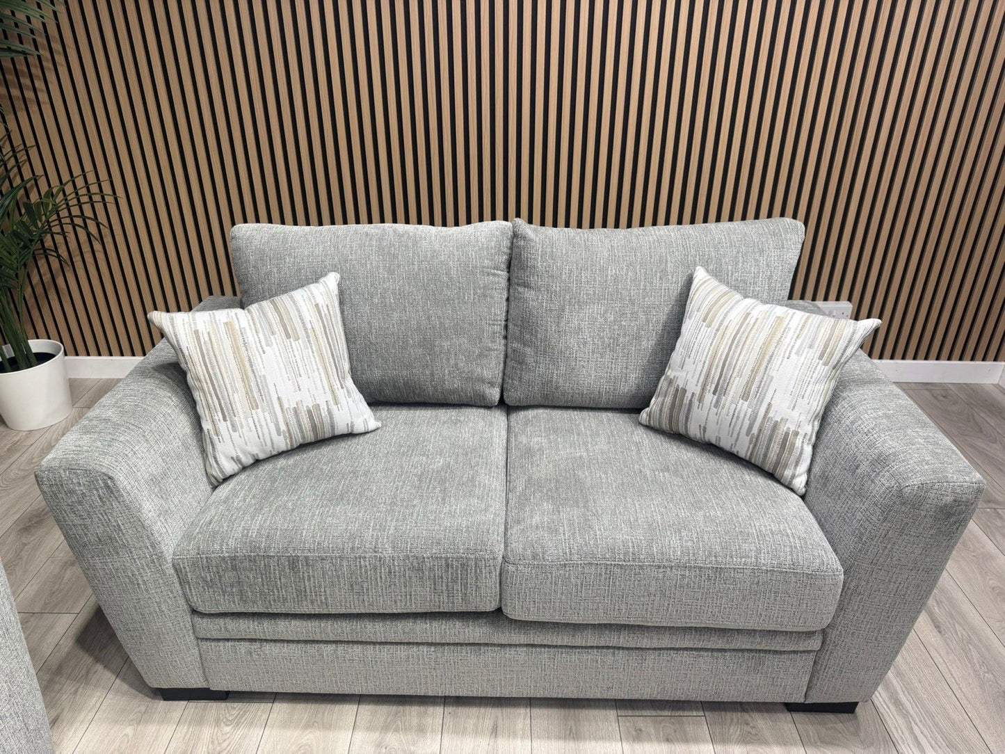 Gray sofa with patterned cushions against a wooden paneled wall.