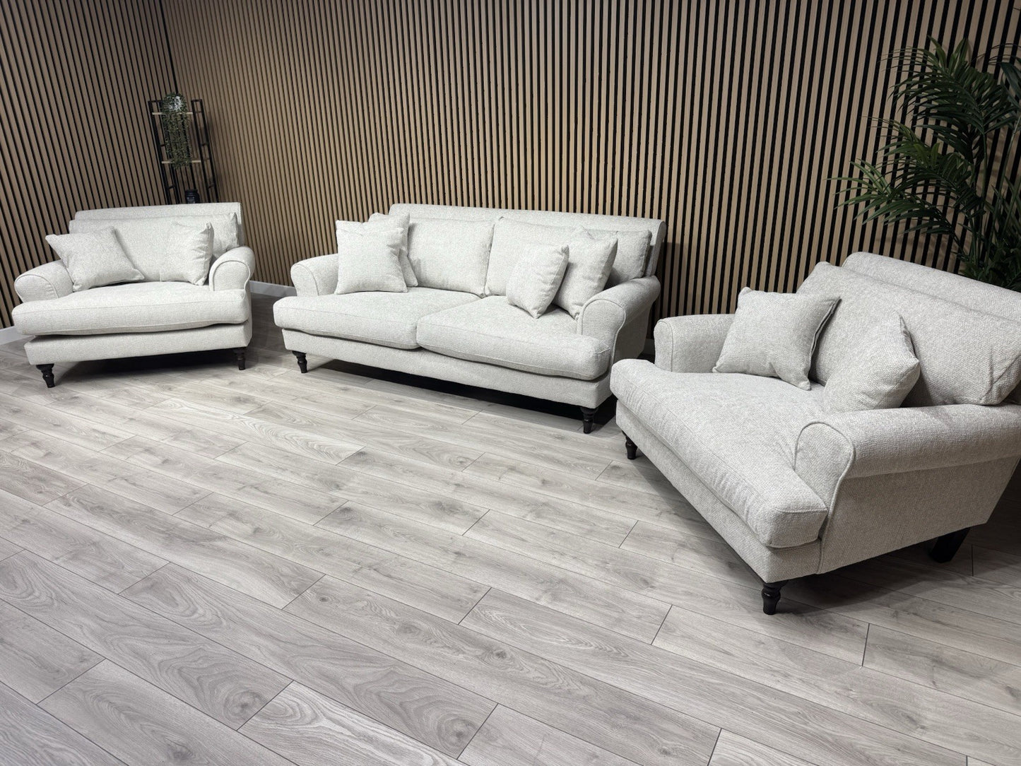 White sofa set in a room with wooden flooring and a striped wall.