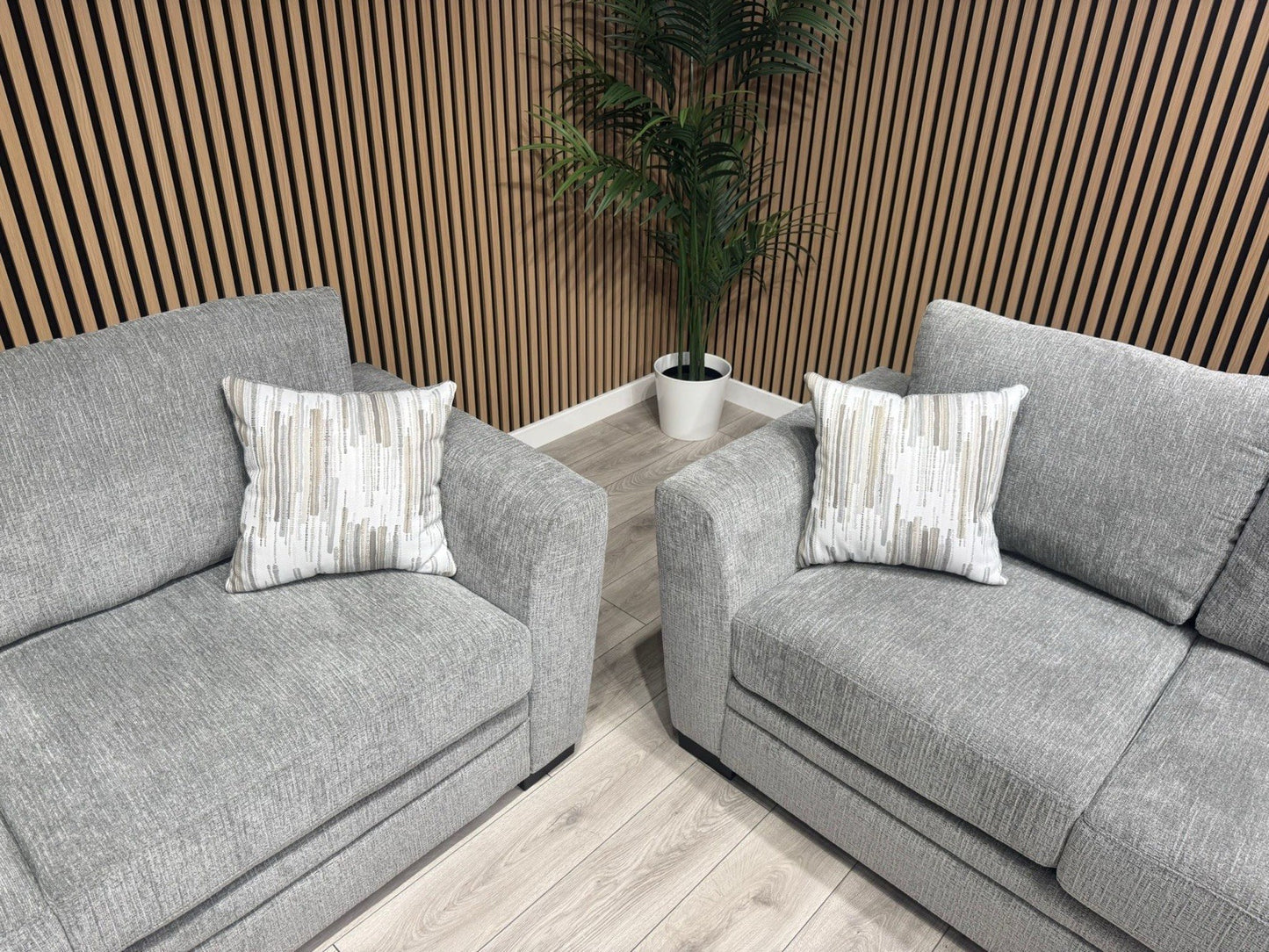 Two gray sofas with patterned cushions in a room with wooden walls and floor.