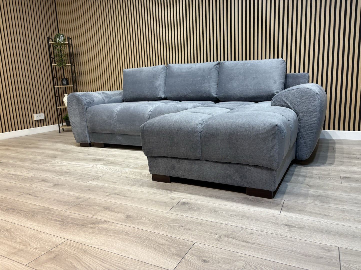 Gray sectional sofa in a room with wooden flooring and a slatted wall.