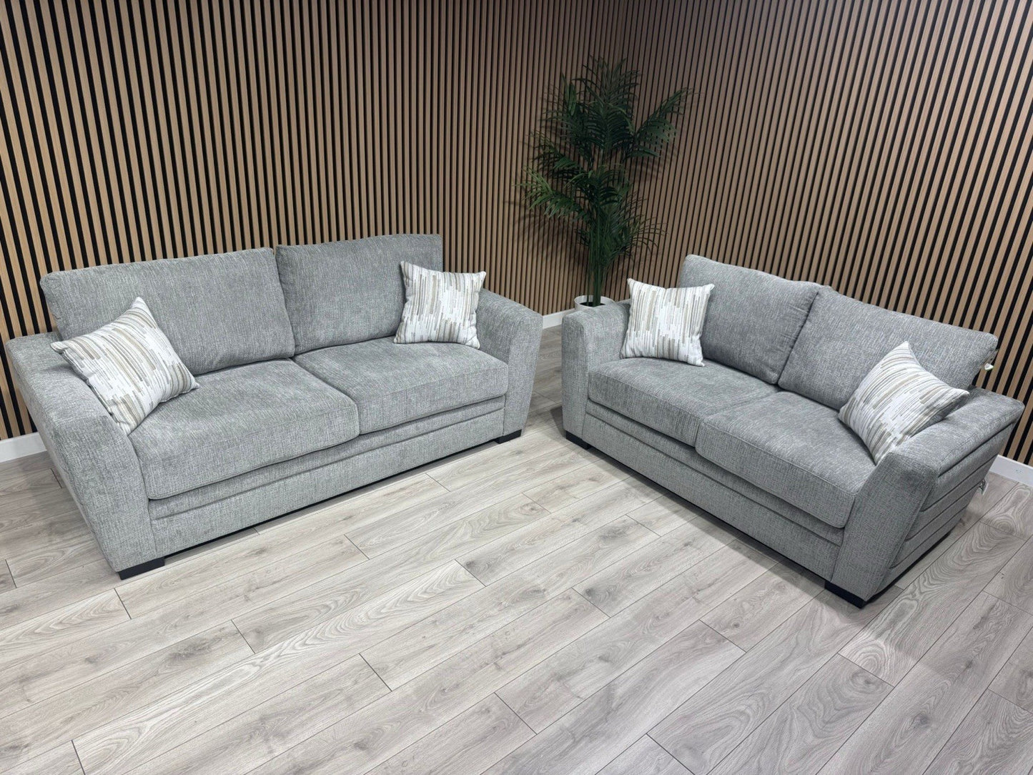 Gray sectional sofa with patterned cushions in a room with wooden flooring and wall.