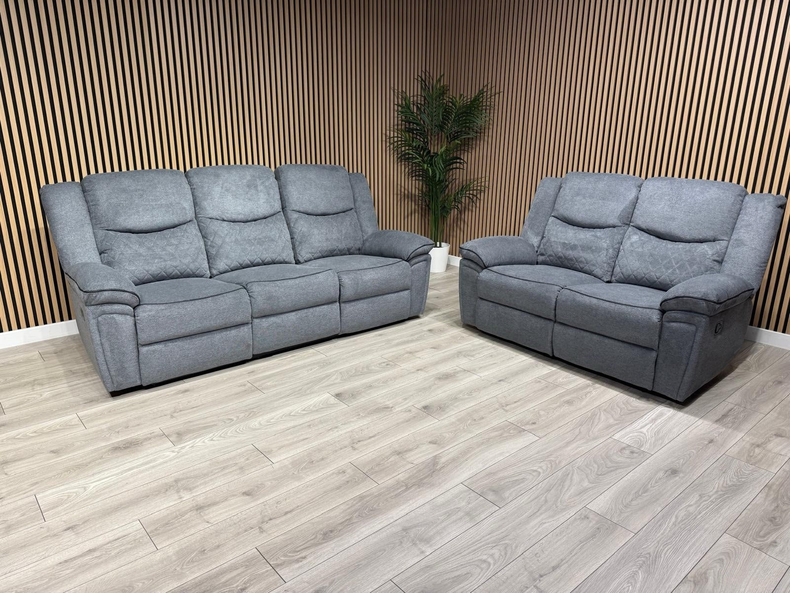 Gray sofa set on a wooden floor with a wooden paneled wall in the background