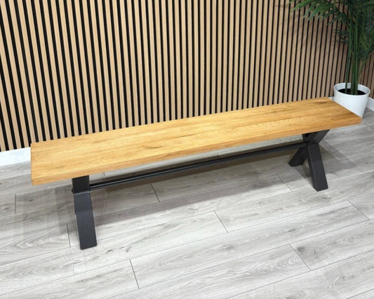 Wooden bench against a slatted wooden wall with a plant in the background.