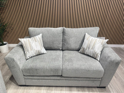Gray sofa with patterned cushions against a wooden paneled wall.