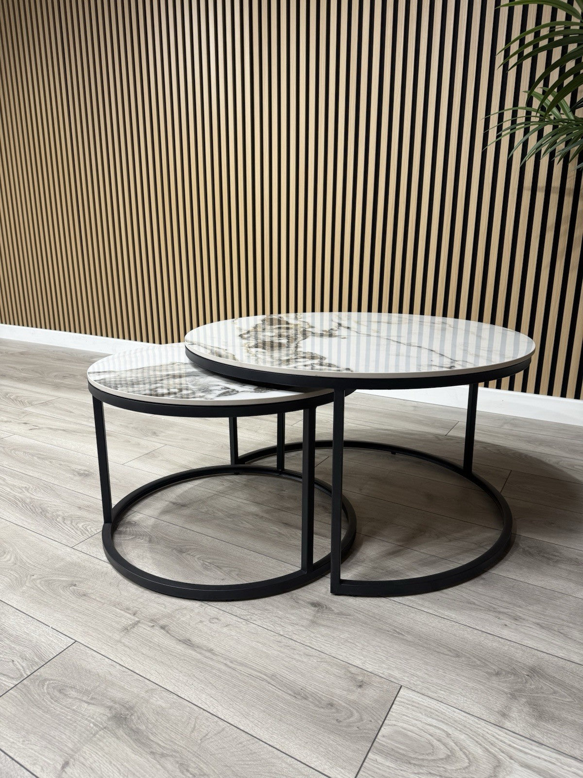 Round coffee table with marble top and black metal base on a wooden floor.