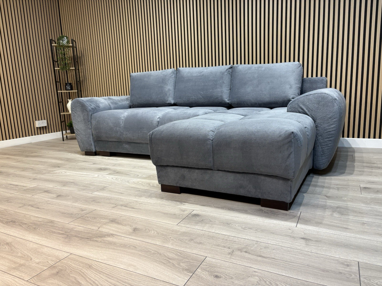 Gray sectional sofa in a room with wooden flooring and a slatted wall.