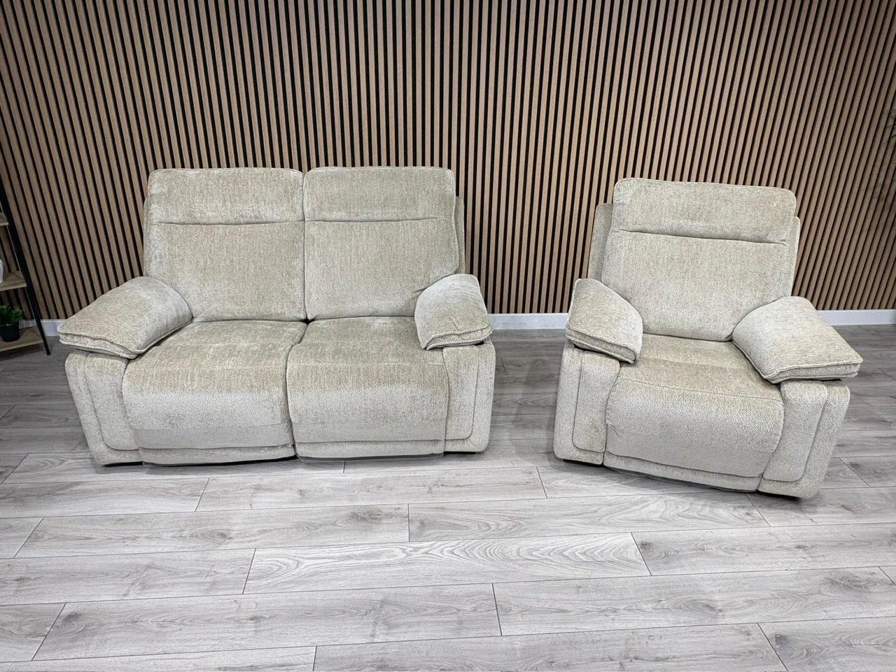 Beige recliner sofa and armchair set against a wooden paneled wall.