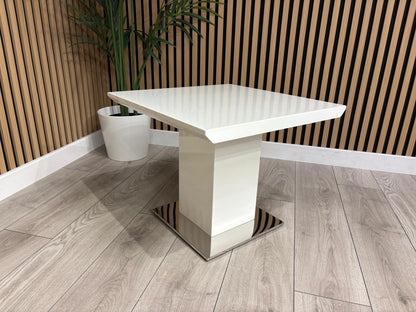 White square dining table with a modern design on a wooden floor.