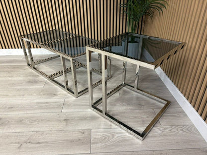 Two modern glass tables with metal frames on a wooden floor.